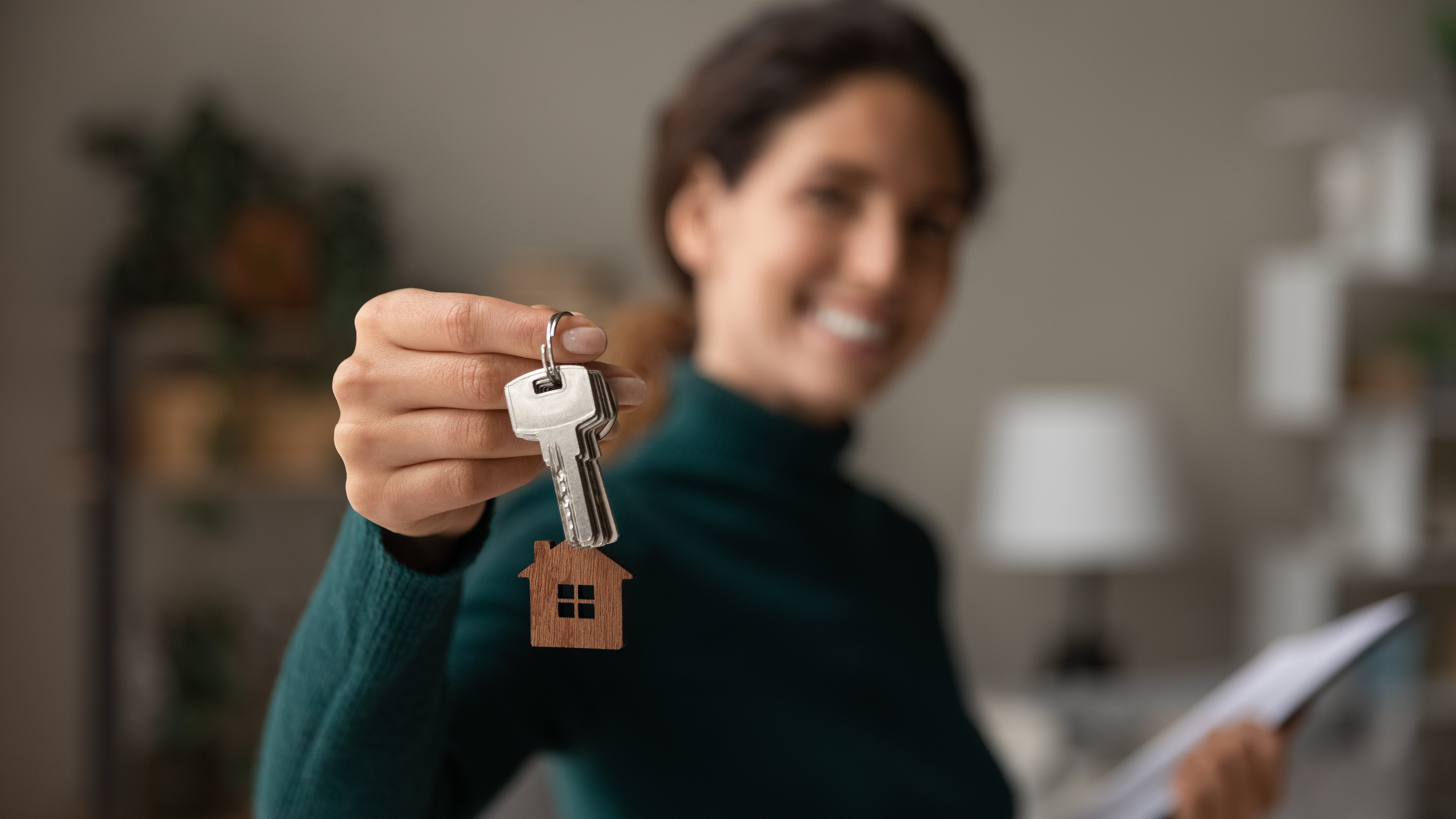 Person holding keys while smiling in the background